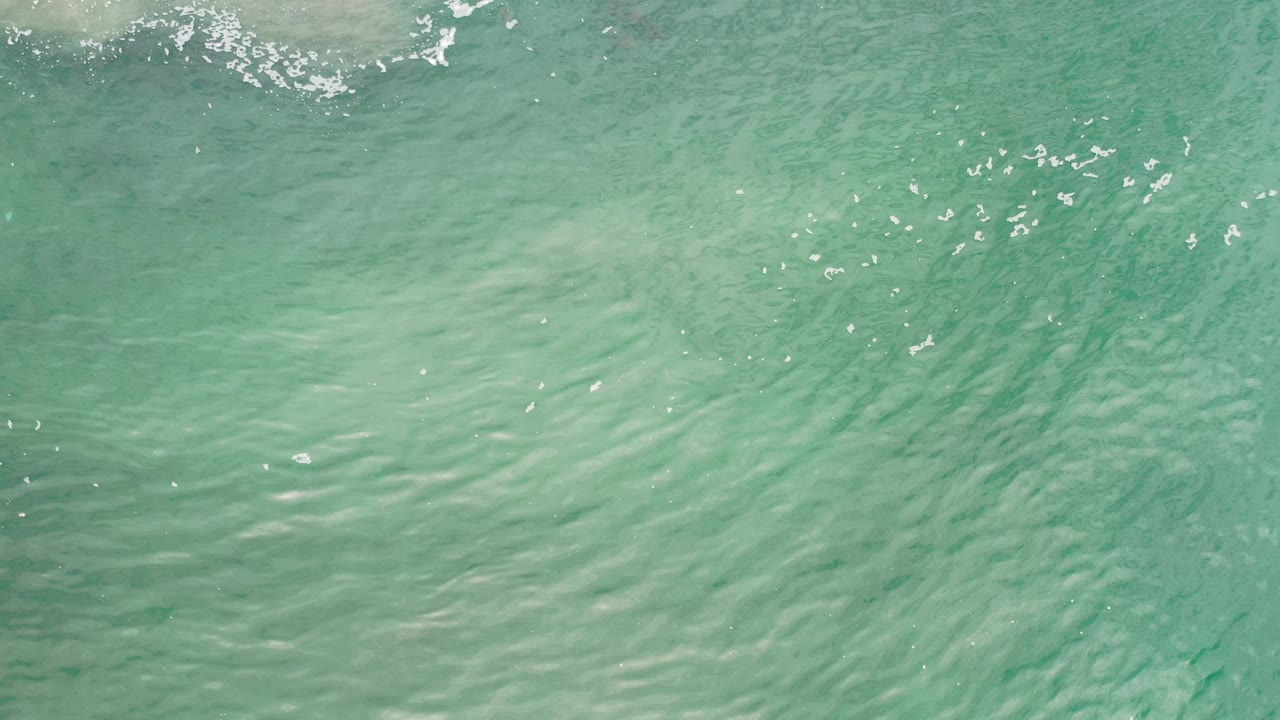 Turquoise ocean water in Los Cabos, Mexico, with a pale rolling crest near the top of the frame and no visible people.
