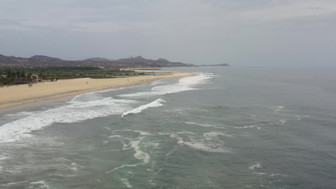 Beach and ocean seen from above with mountains on the horizon.