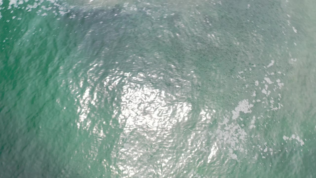 Turquoise rippled water in Los Cabos, Mexico, with a bright sun reflection low in the frame and no visible people.