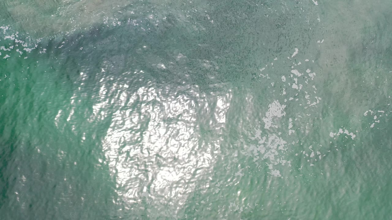 Sunlit turquoise water with curved ripple patterns.