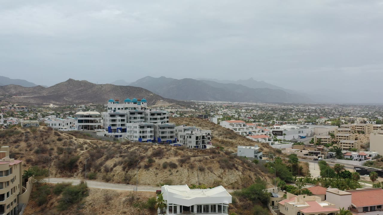 Urban hillside and mountains under overcast sky
