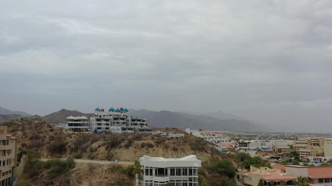 Hillside buildings below gray clouds