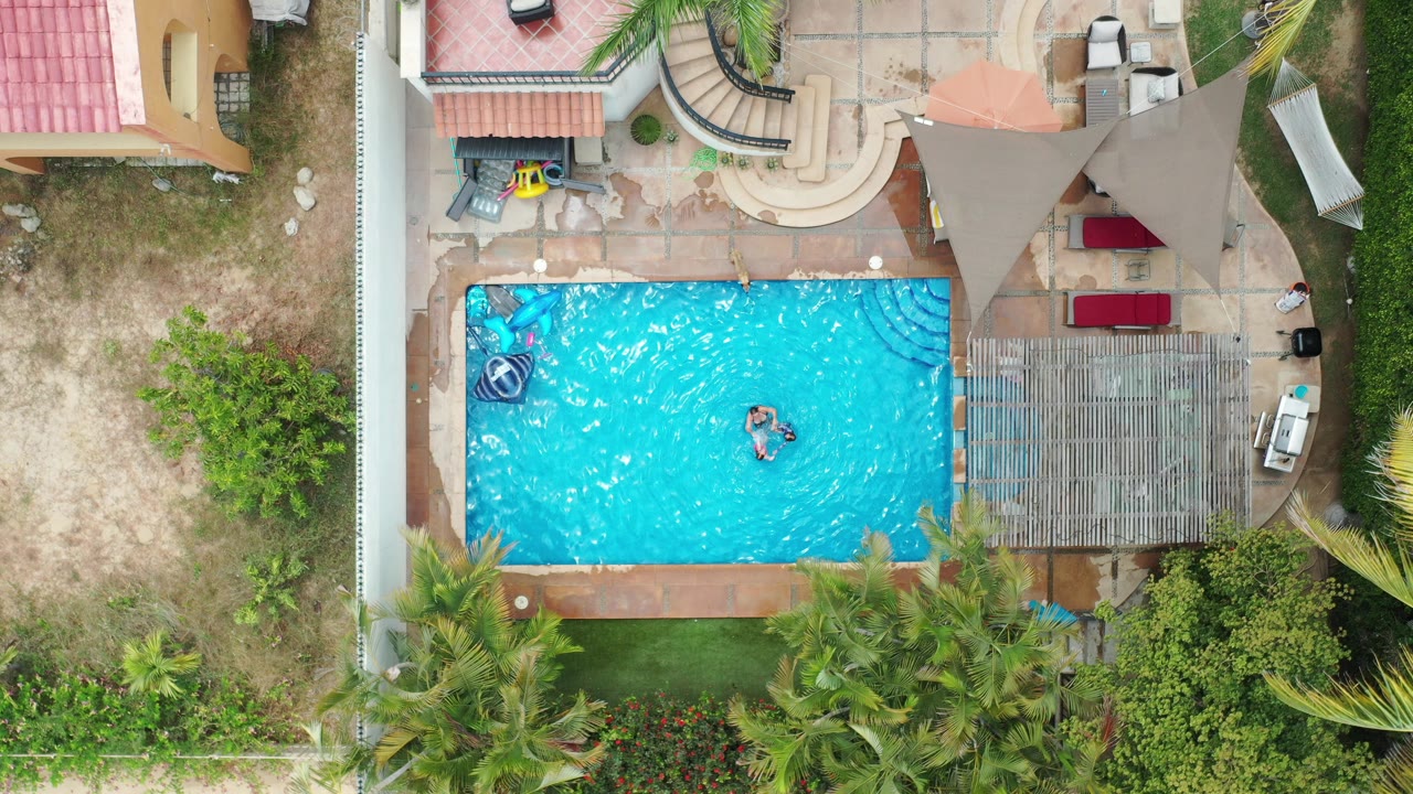 Overhead view of a backyard pool with one child in the water.