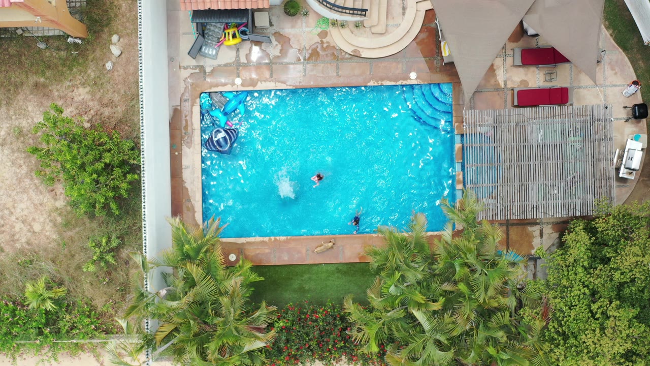 Overhead view of a backyard swimming pool with two people in the water.