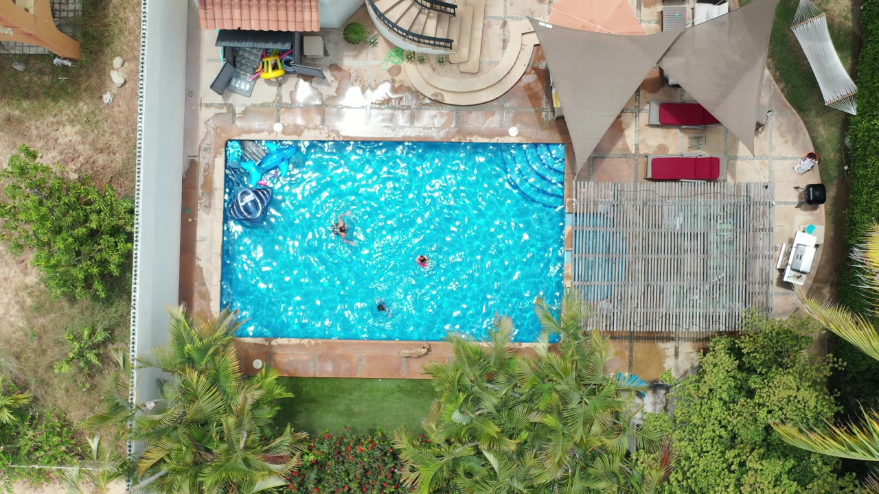 Overhead view of a backyard swimming pool with people in the water.