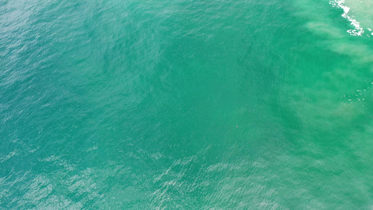 Aerial view of green-blue sea with pale underwater areas.