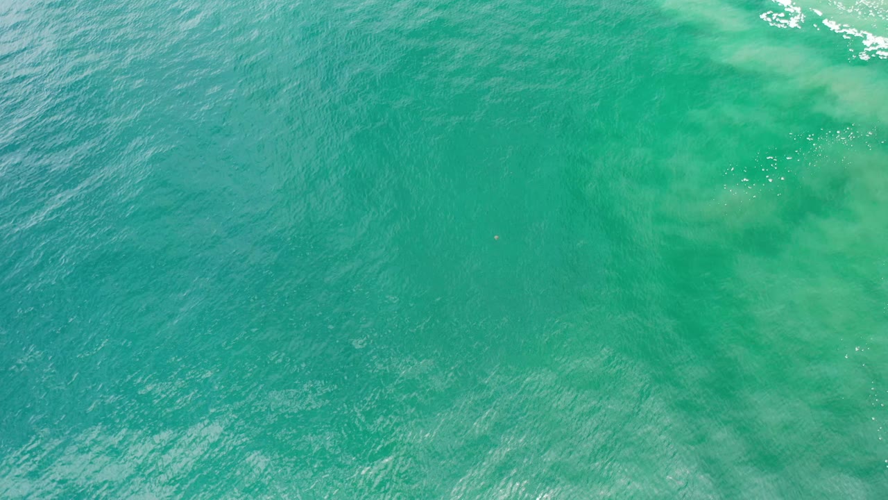 Green turquoise sea surface in Los Cabos, Mexico, with ripples across the frame, soft pale shapes under the water, and no visible people.