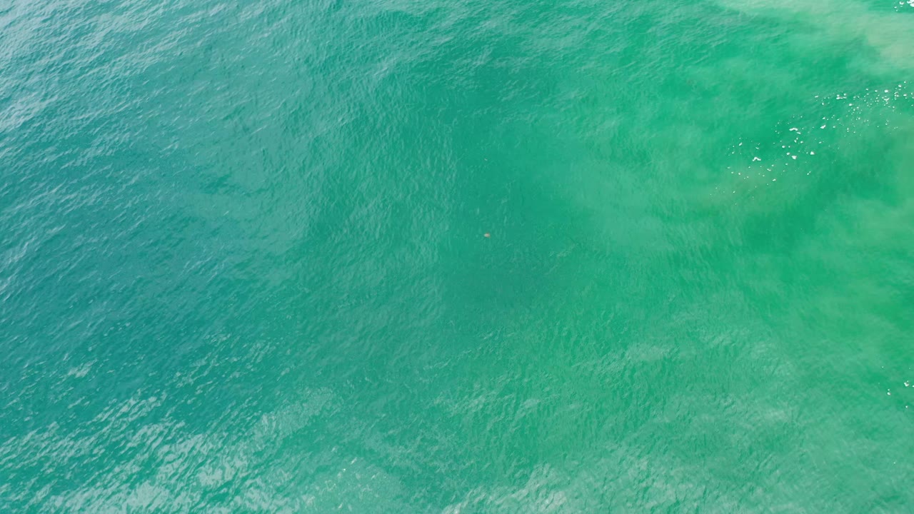 Straight-down ocean view in Los Cabos, Mexico, with green-blue water, subtle surface movement, and no visible people.