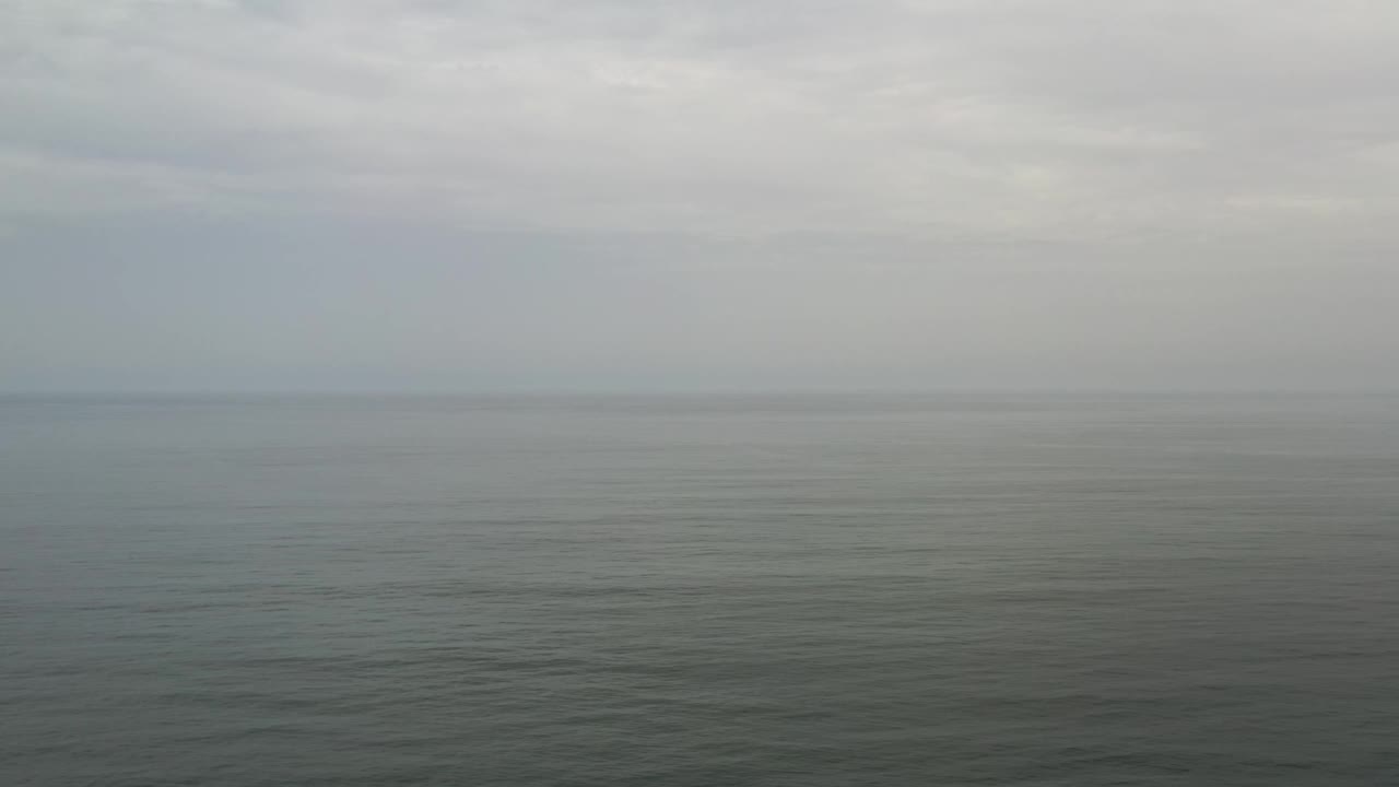 Los Cabos open water fills the lower frame while pale clouds stretch across the horizon, with no visible people.