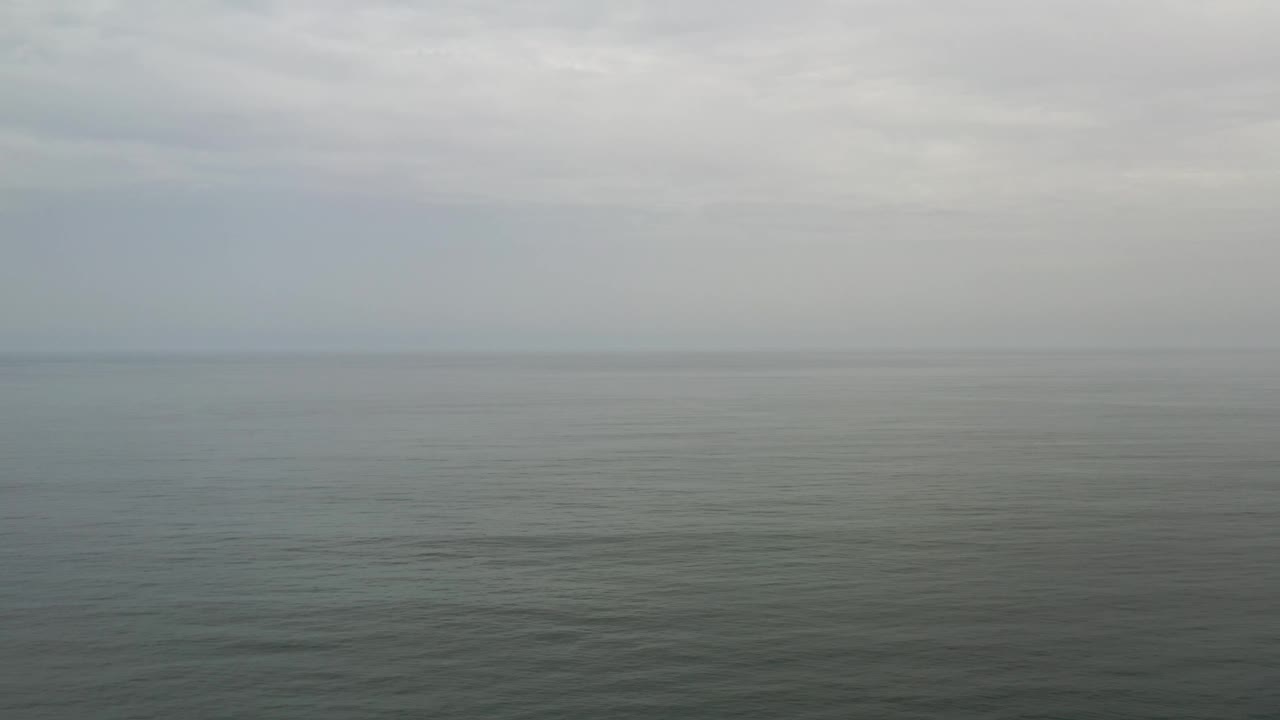 A broad view of muted ocean water in Los Cabos, Mexico, with low gray cloud cover and no visible boats, buildings, or people.