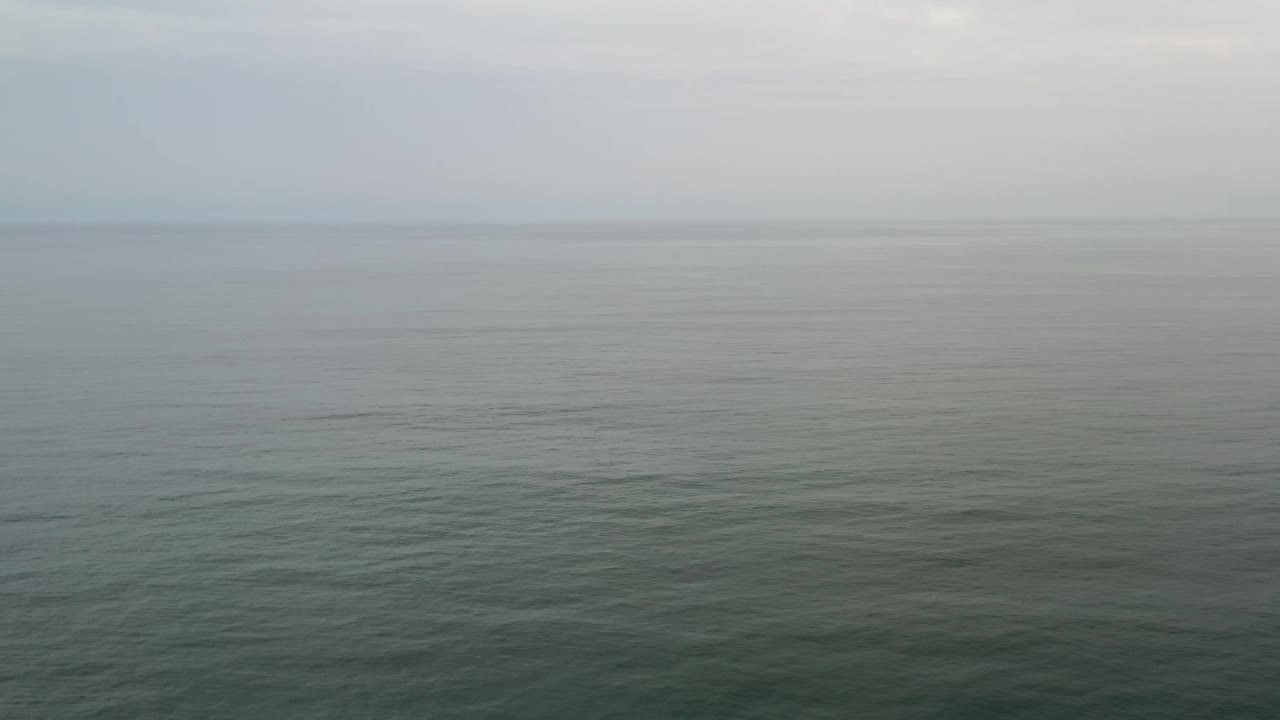 Calm gray ocean in Los Cabos, Mexico, with the horizon softened by mist and no visible people or structures.