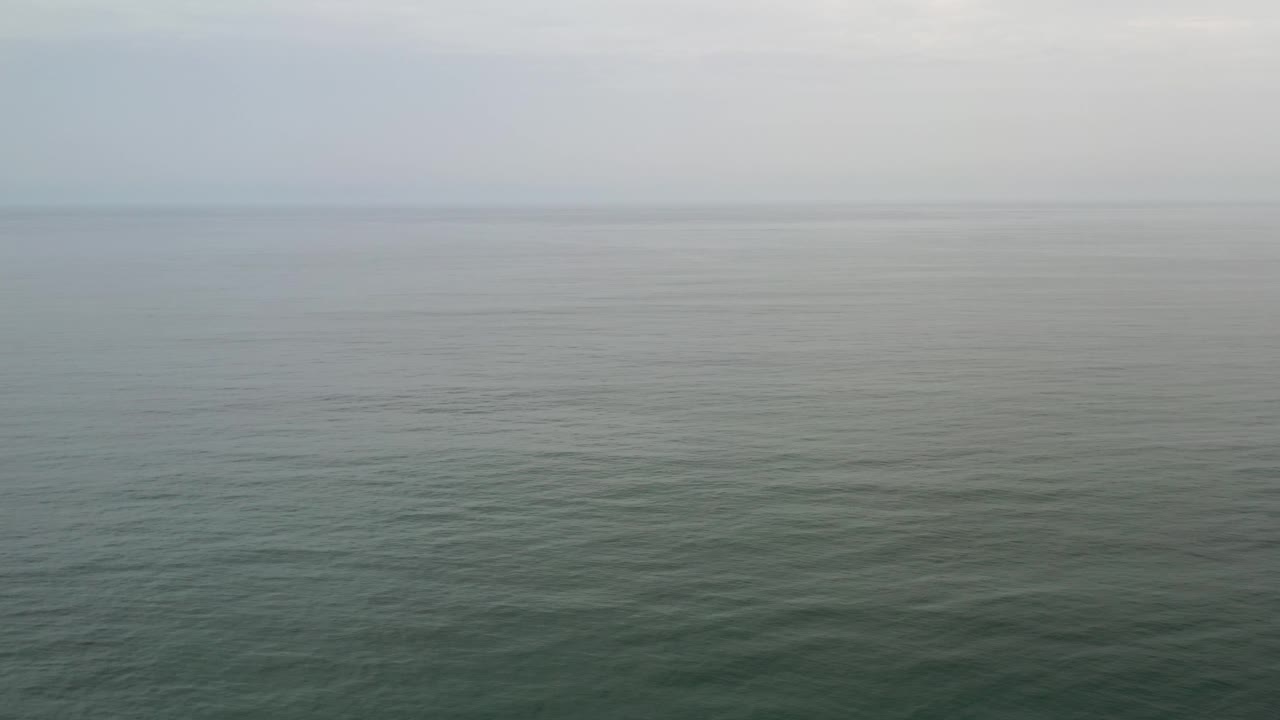 Foggy ocean horizon above softly rippled water