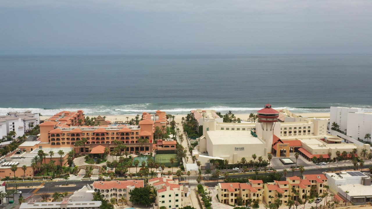 Aerial view of coastal buildings, beach, and ocean horizon.