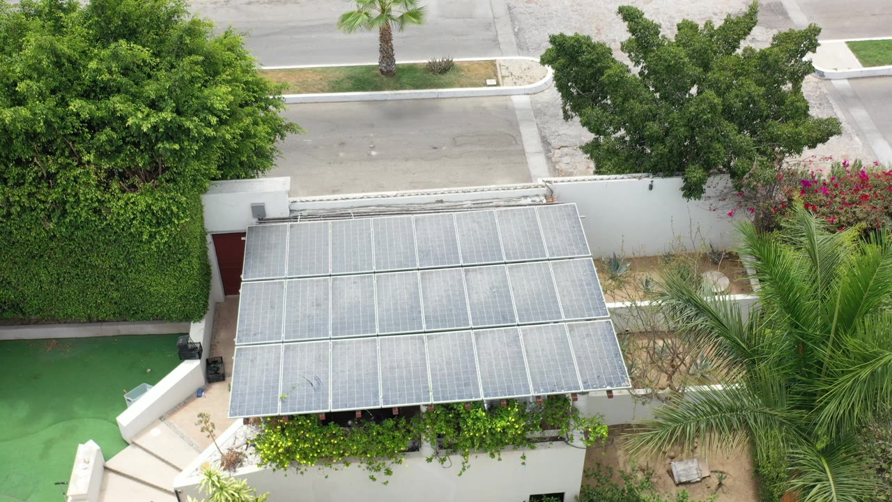Second frame shows the Los Cabos house frontage from above, with the canopy centered, thick greenery on both sides, a quiet road beyond, and no visible people.