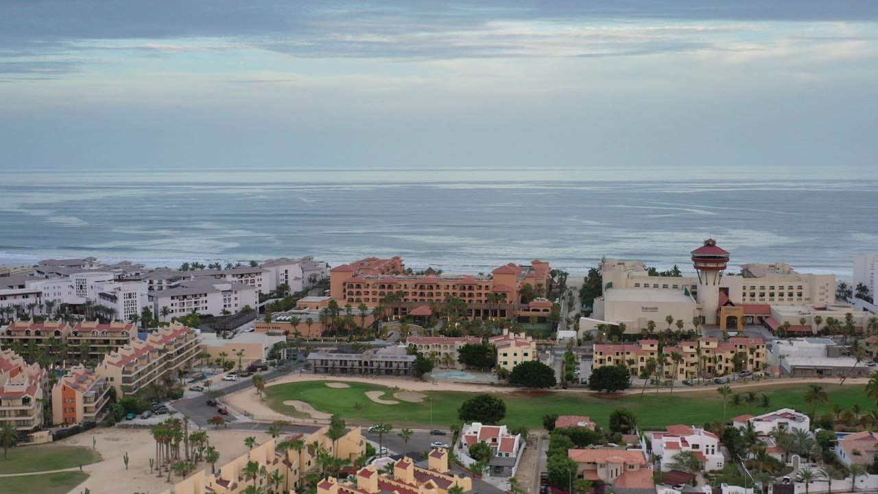 Coastal town rooftops and ocean horizon seen from above.