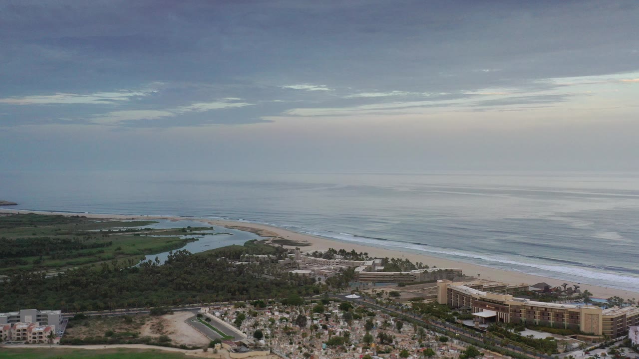 Aerial coastline with beachfront buildings and ocean horizon