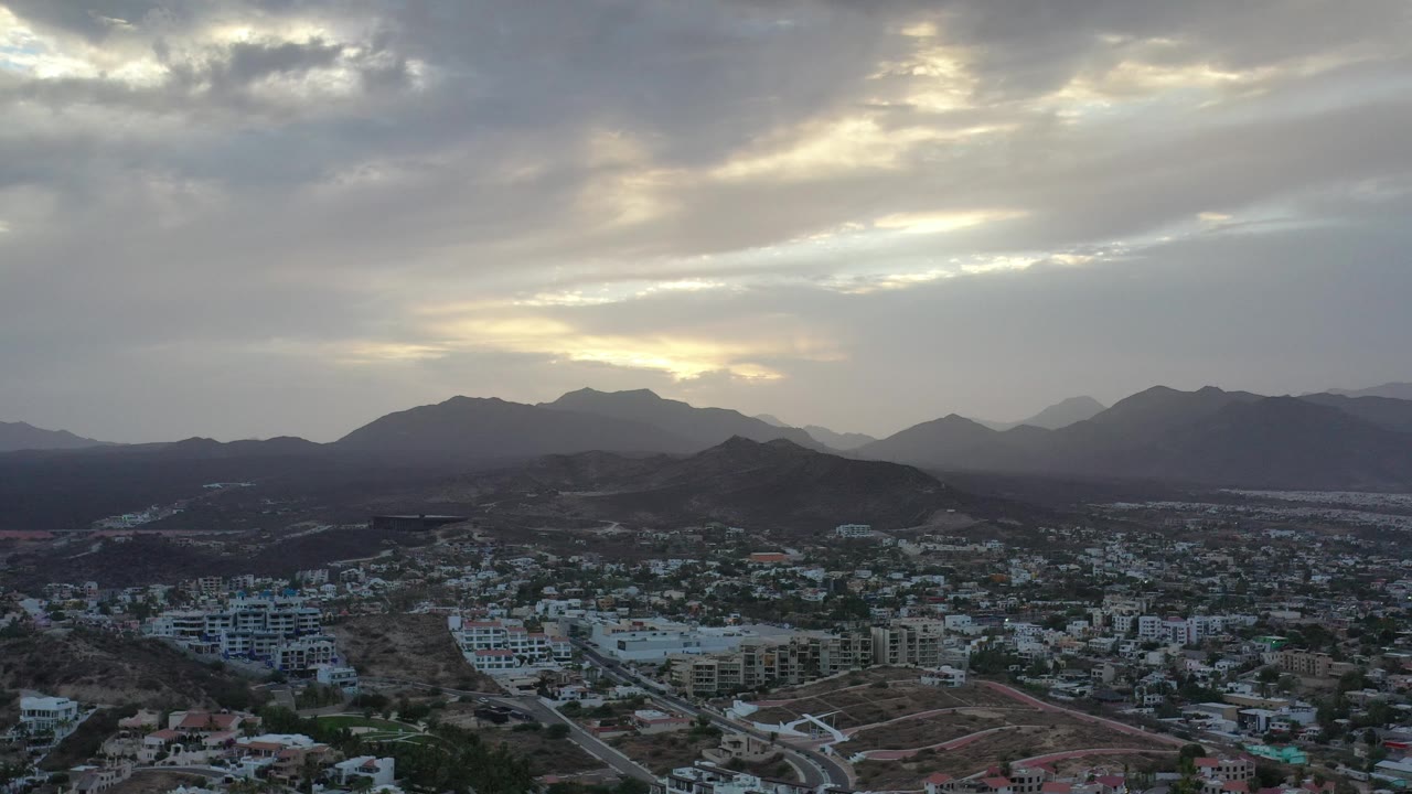 Los Cabos townscape with layered mountains at dusk-like light