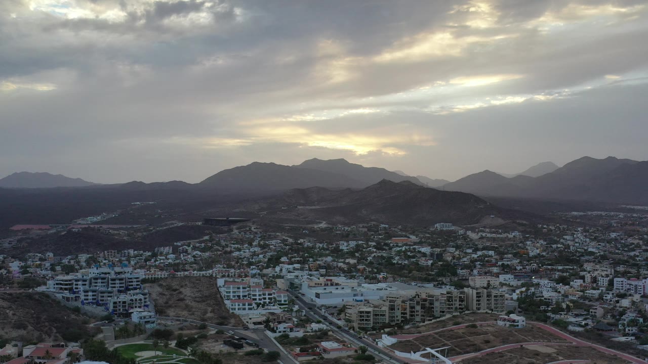 Elevated view across Los Cabos toward cloudy mountain ridges.