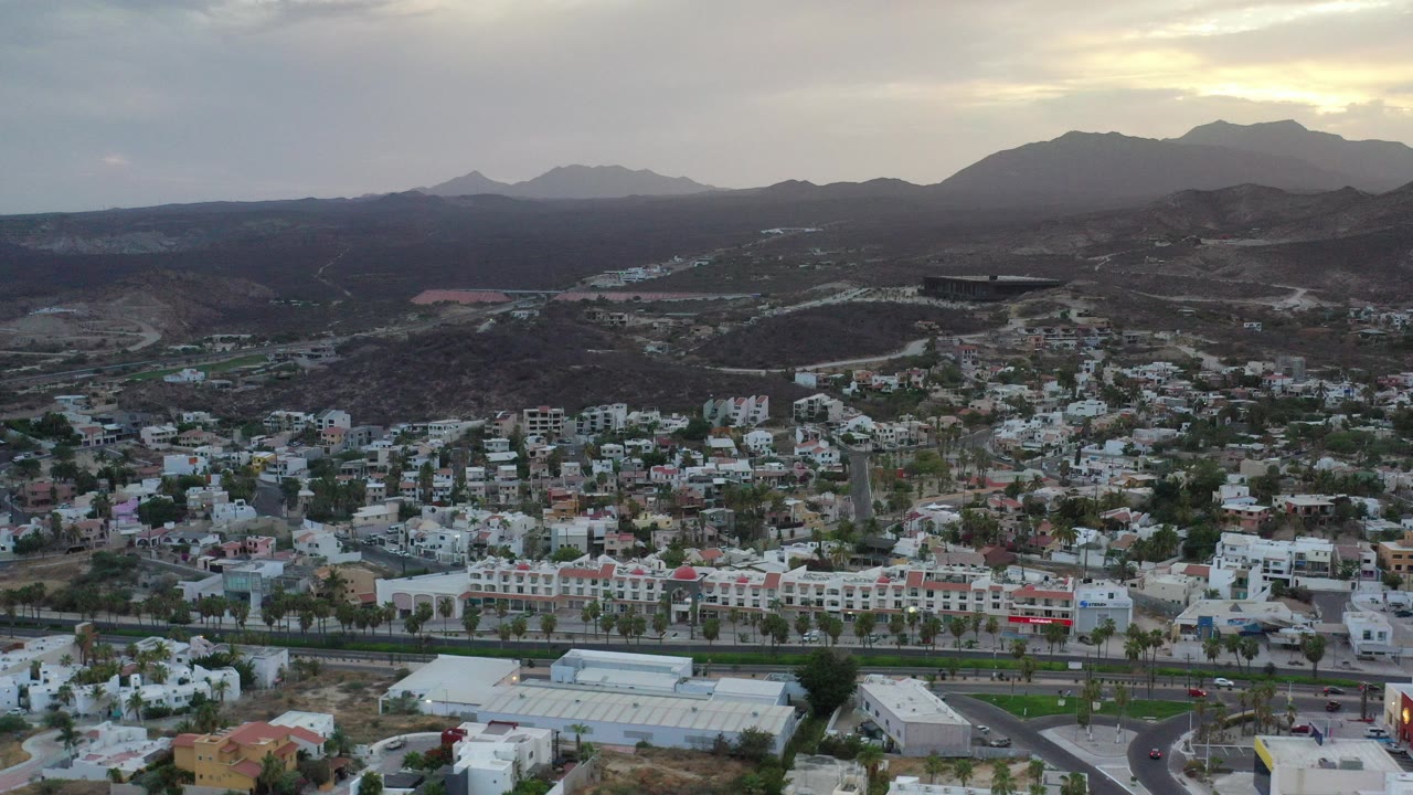 Aerial view of houses below dry hills and distant mountains