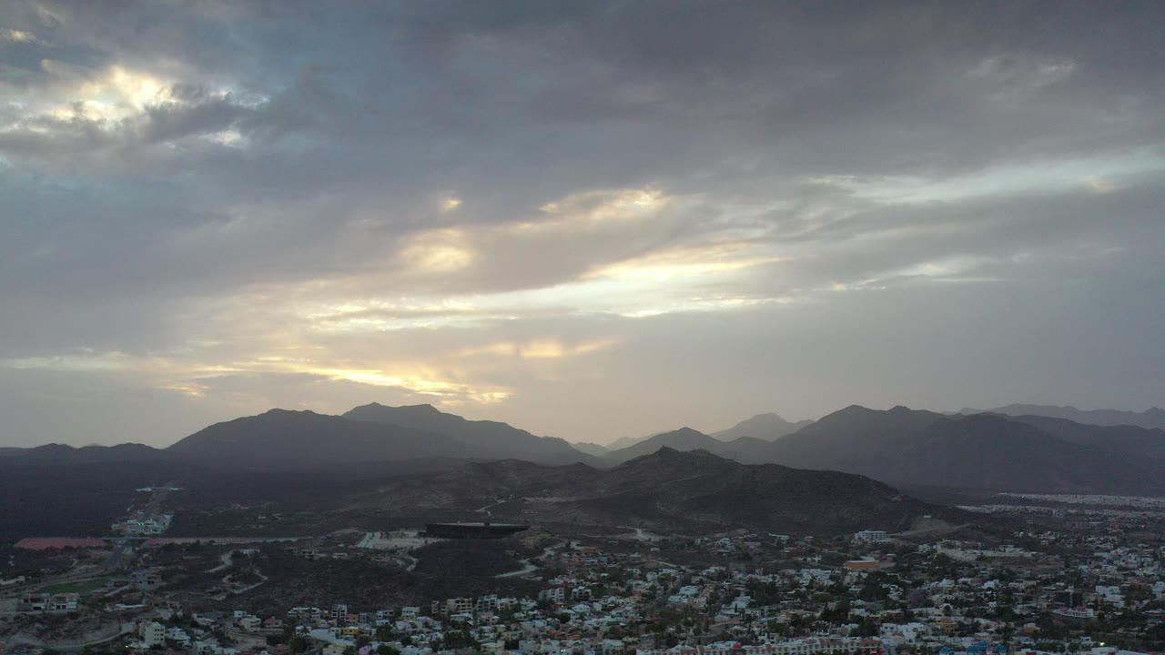 Cloudy sky over mountain ridges and a town below