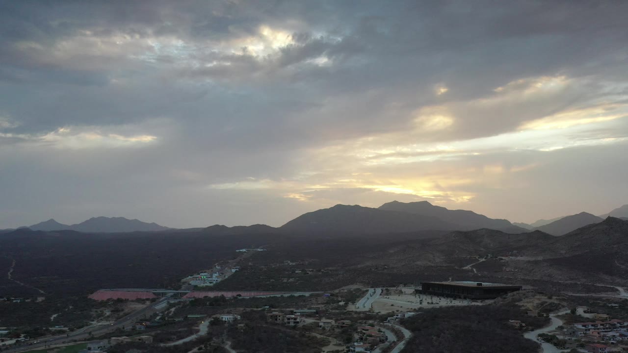 Aerial landscape of rugged hills, mountain ridge, and cloudy sunset sky.