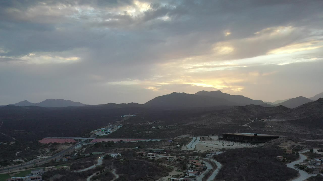 High view of roads and buildings with mountains under bright clouds