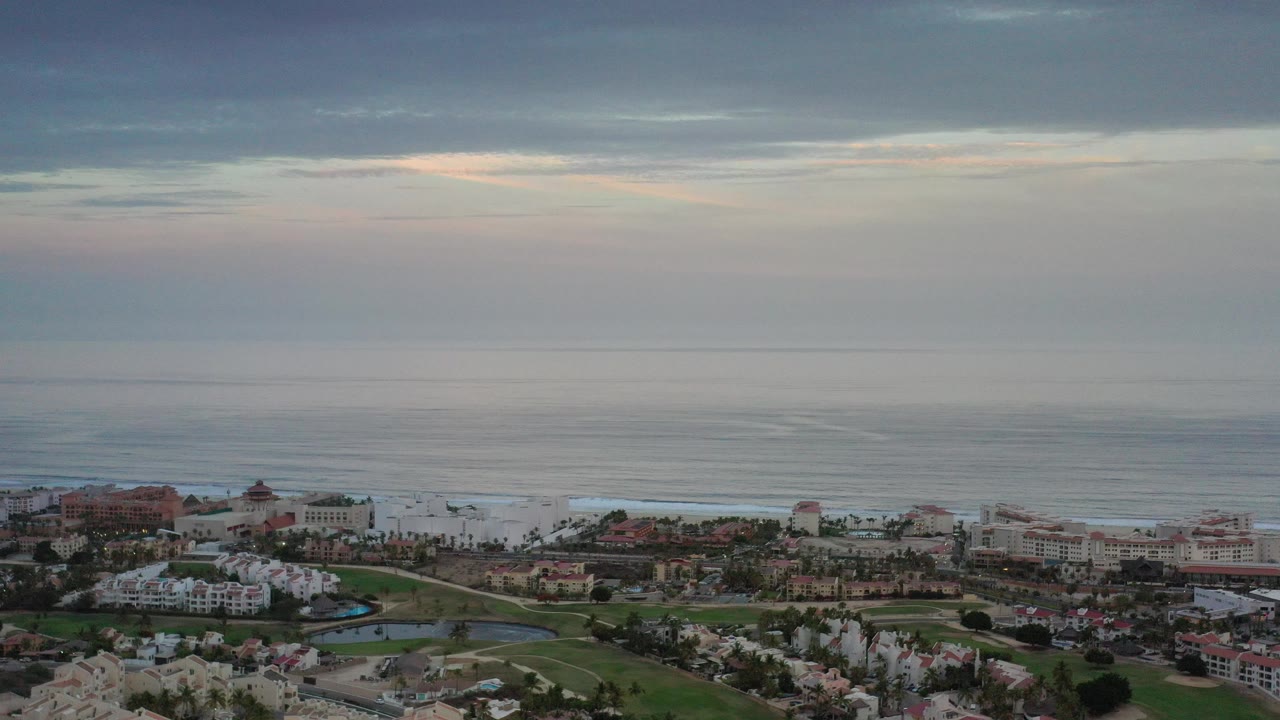 Aerial view of coastal buildings and ocean under cloudy sky
