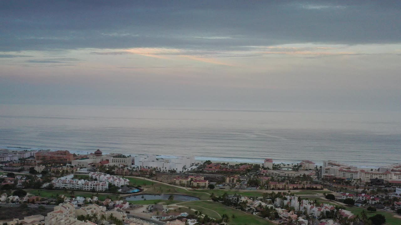Aerial view of coastal buildings below a cloudy ocean horizon.