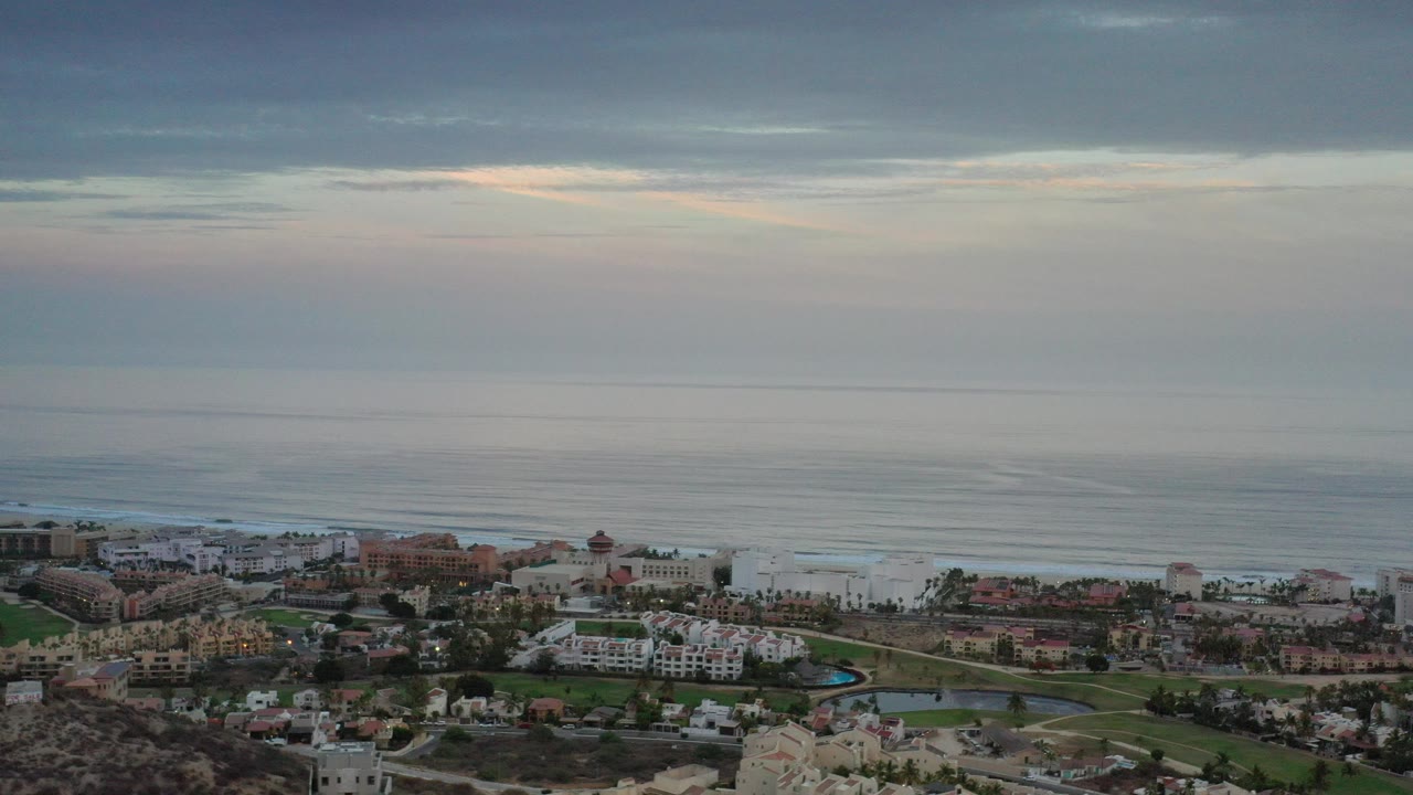 Aerial view of coastal buildings below a cloudy ocean horizon.