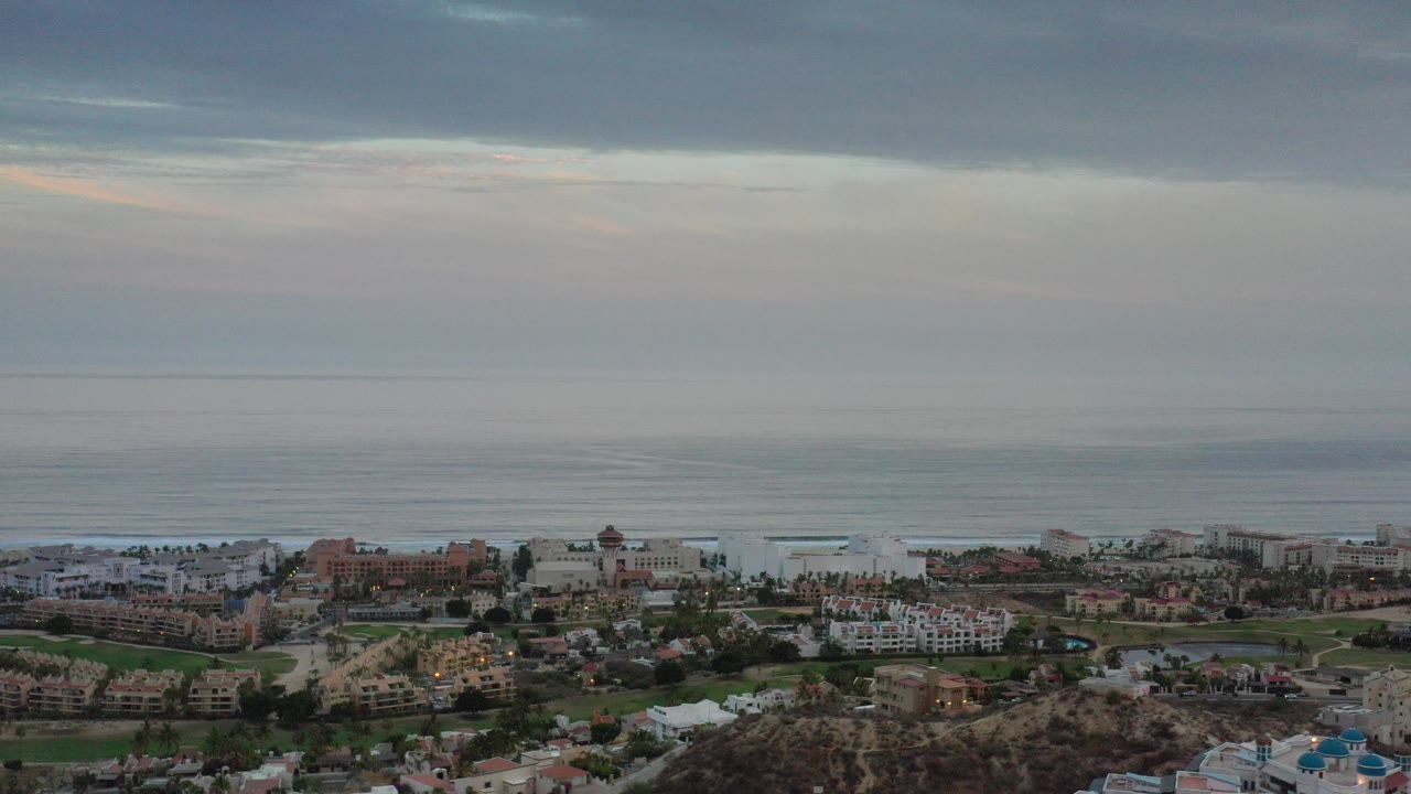 Wide coastal city view under gray clouds with ocean horizon