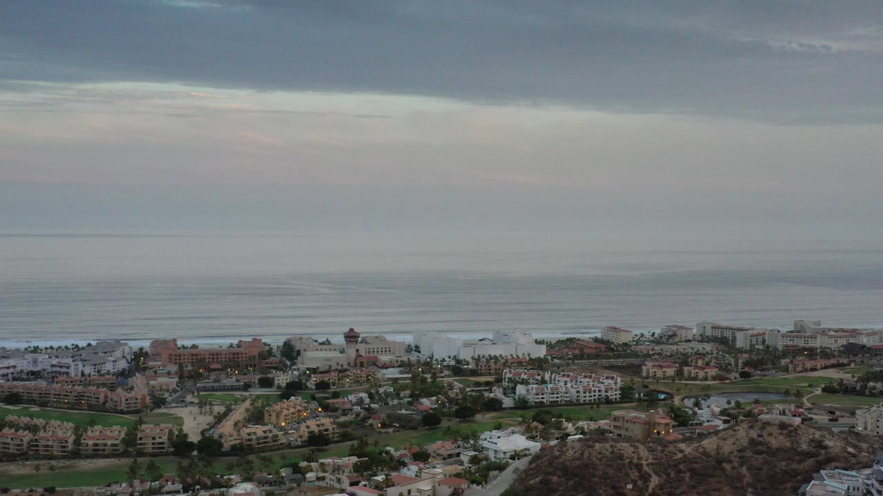 Wide aerial view of a coastal city under heavy clouds.