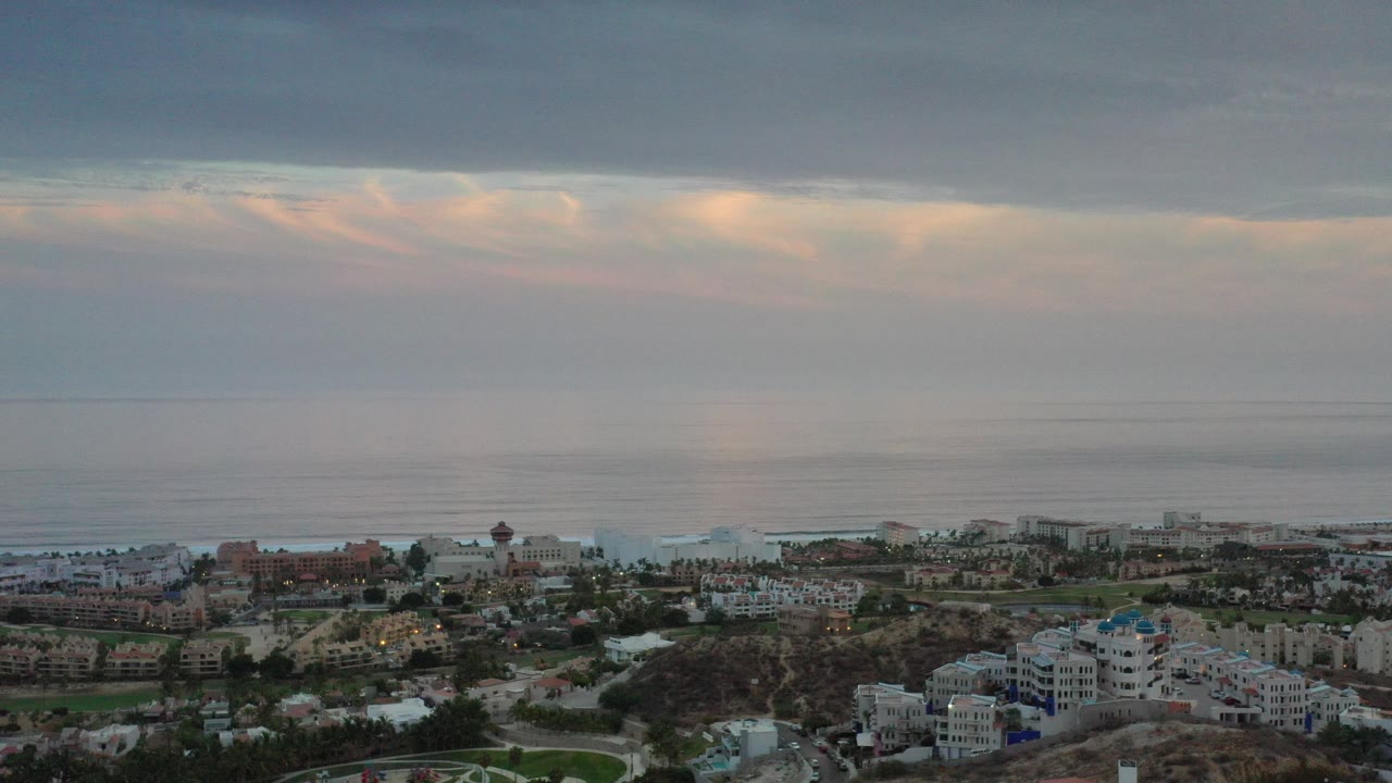 Aerial view of coastal homes below an overcast ocean horizon.