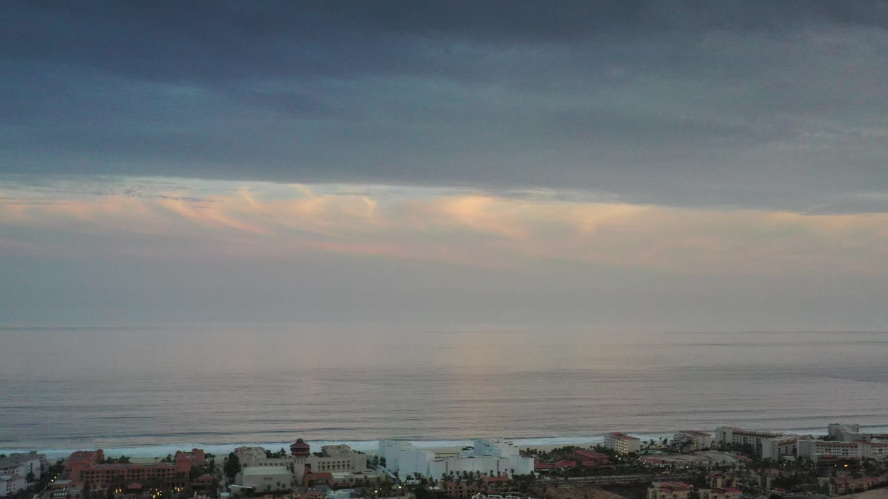 Muted sunset sky over ocean and beachfront roofs