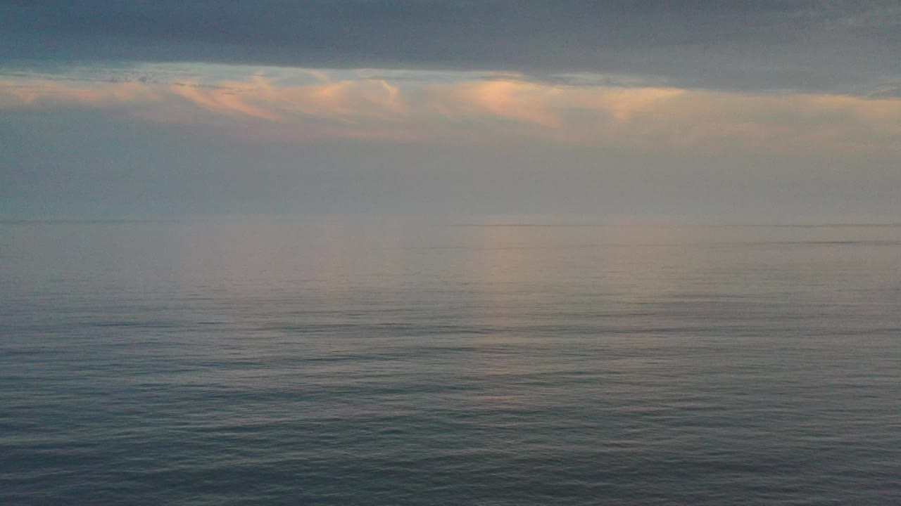 Cloudy horizon over still-looking ocean water.