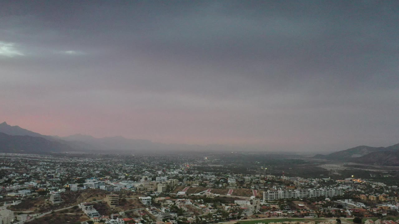 City below a heavy gray sky with mountains on the horizon.