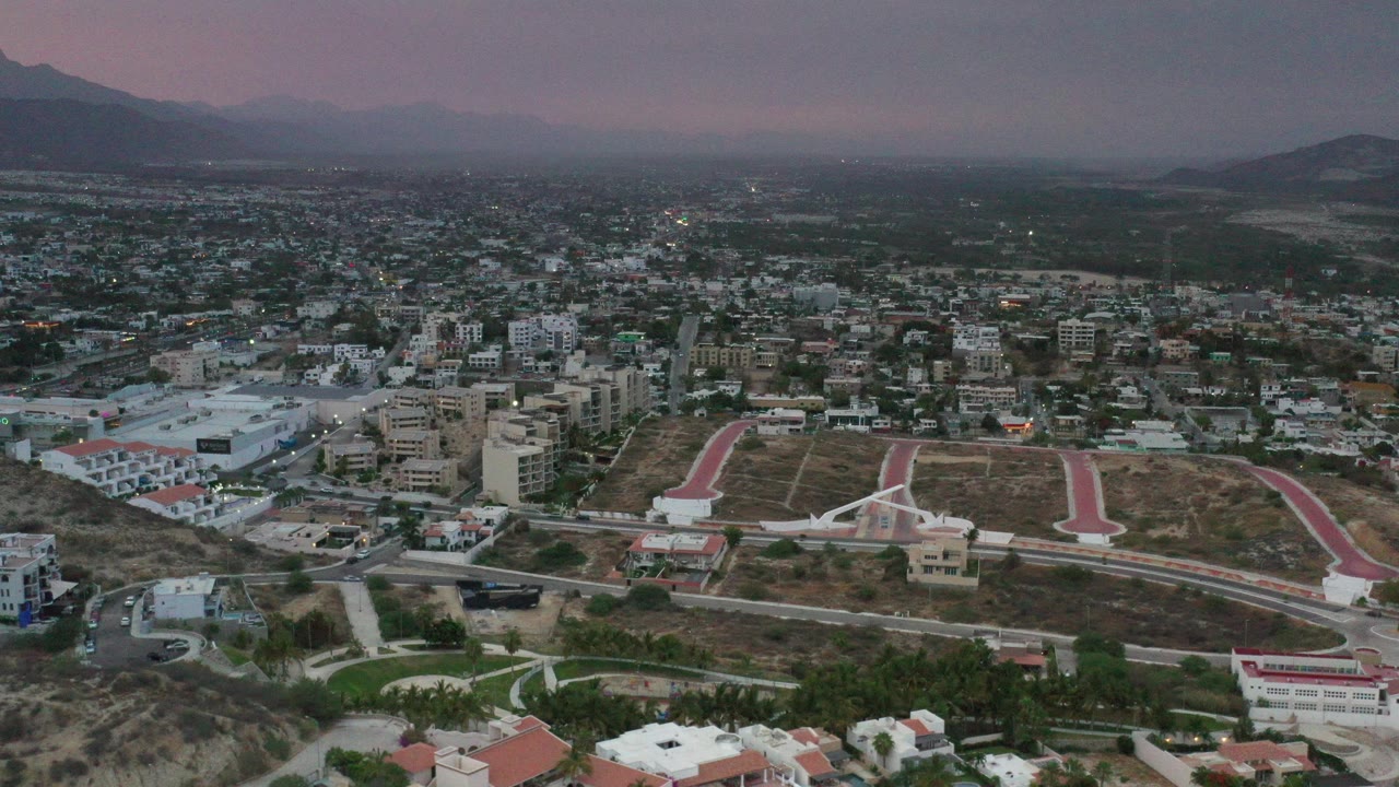 Wide aerial city view with mountains under cloudy sky