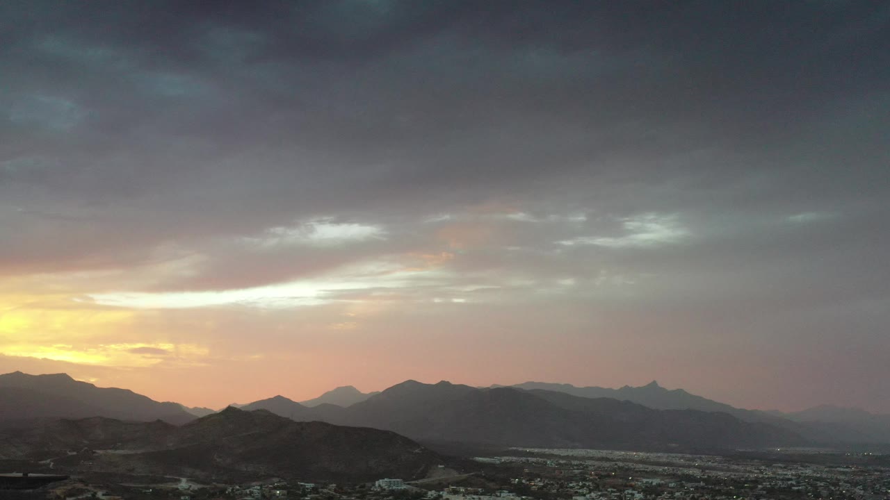 City and mountains beneath a cloudy sunrise sky