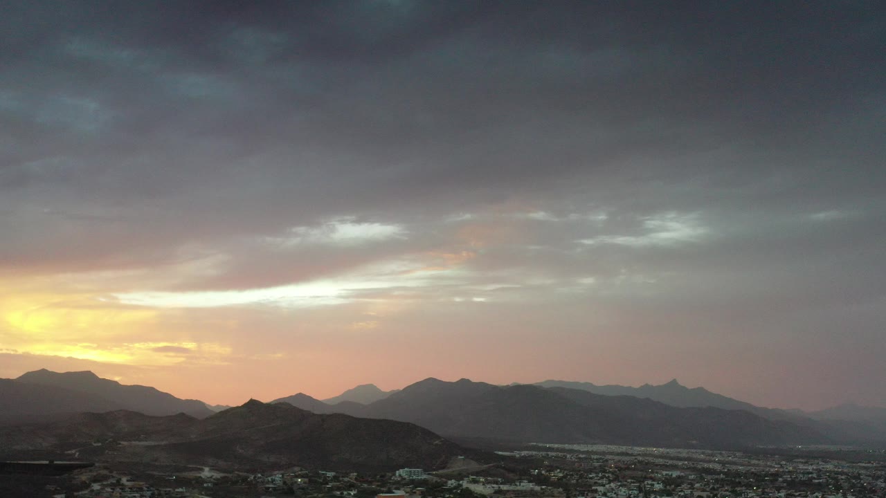 Sunset clouds over a city and mountain ridges