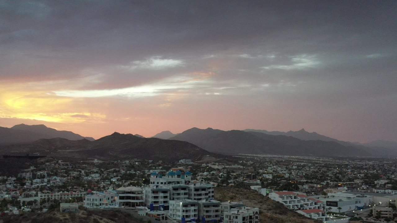 Los Cabos city buildings below mountains at sunset
