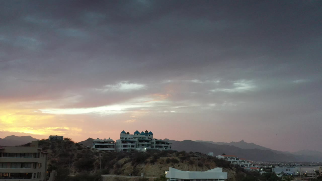 Hilltop buildings beneath a cloudy dawn sky.