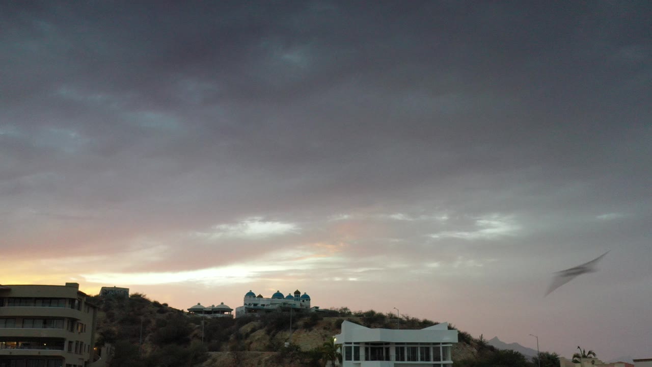 Hillside homes under dark sunset clouds