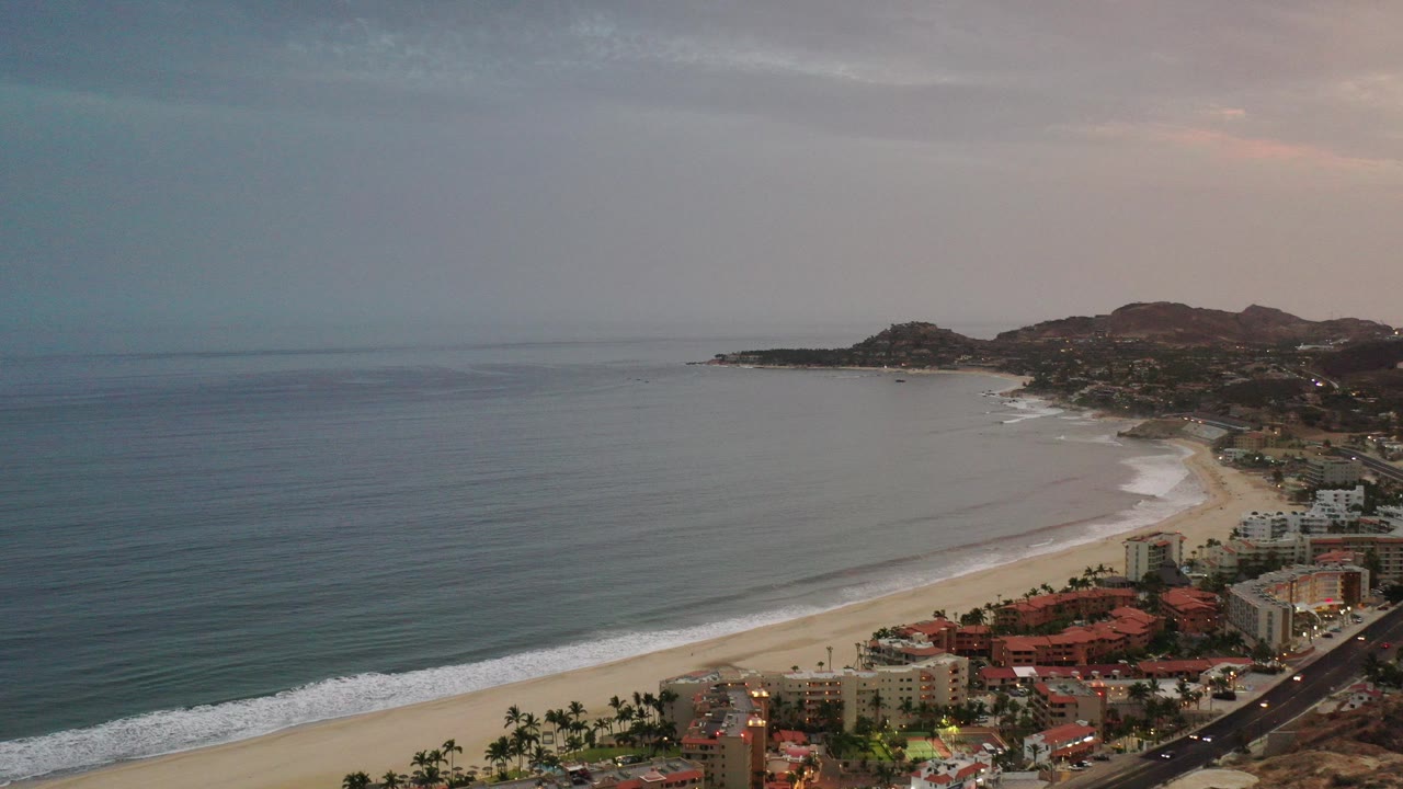 Aerial view of a beach city beside calm ocean at dusk