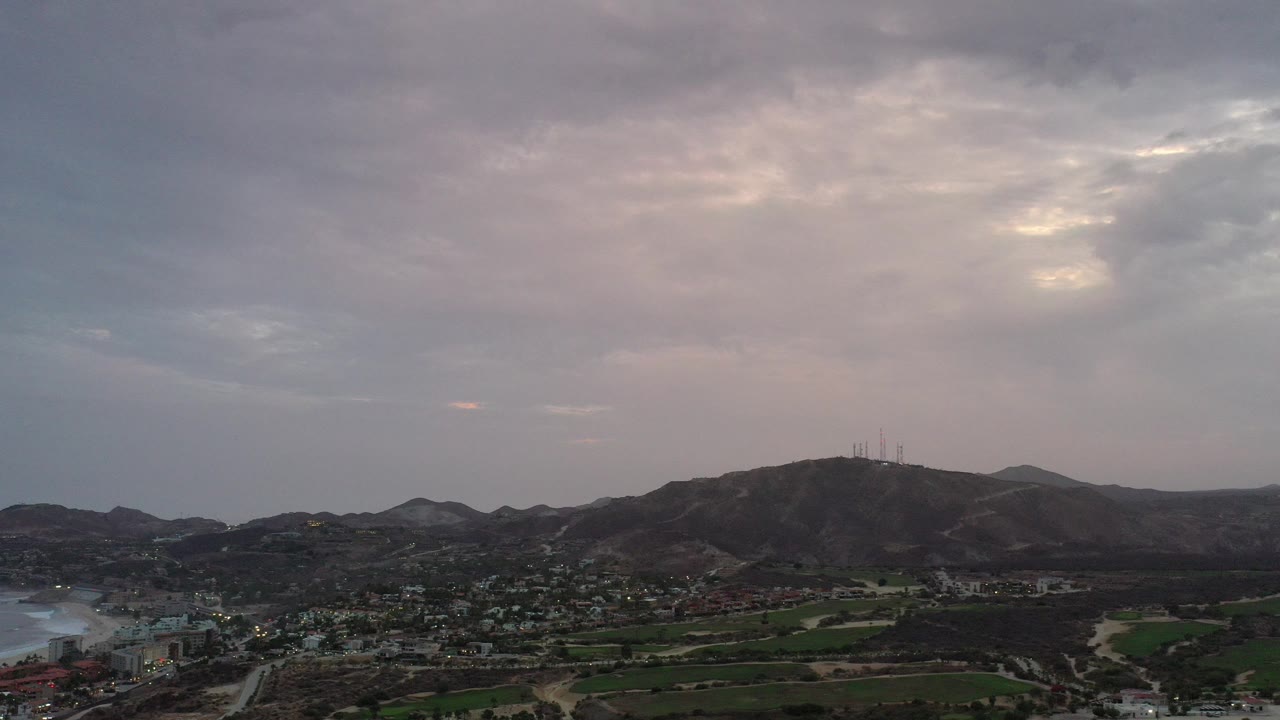 Aerial view of a town, fields, mountains, and cloudy purple sunset sky.