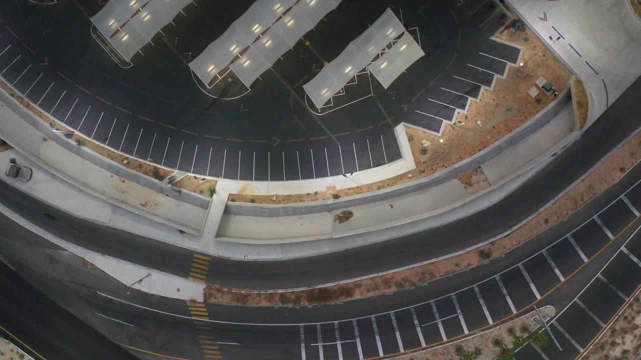 Aerial view of looping roadways, sidewalks, and mostly empty parking stalls.