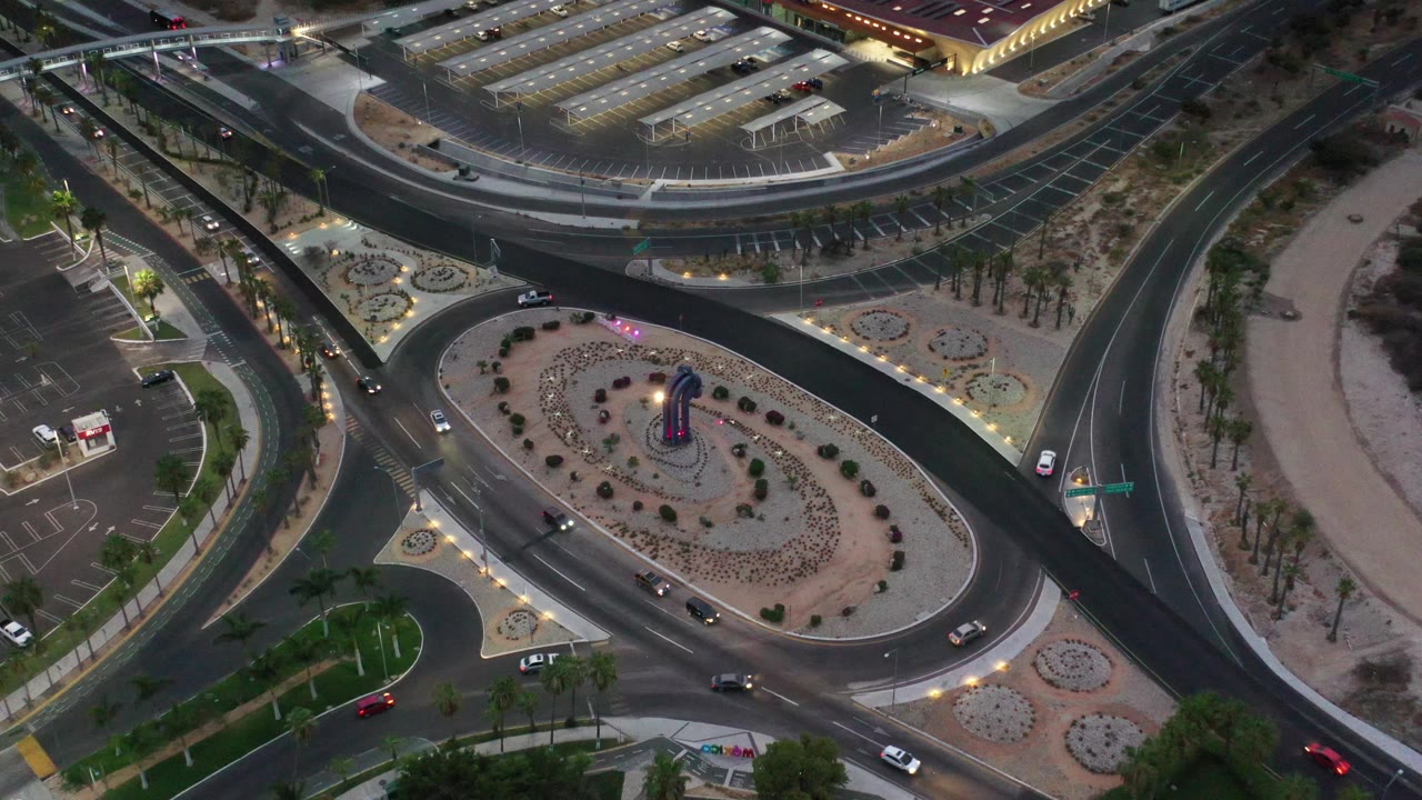 Top-down view of a divided road curving past a landscaped traffic island.