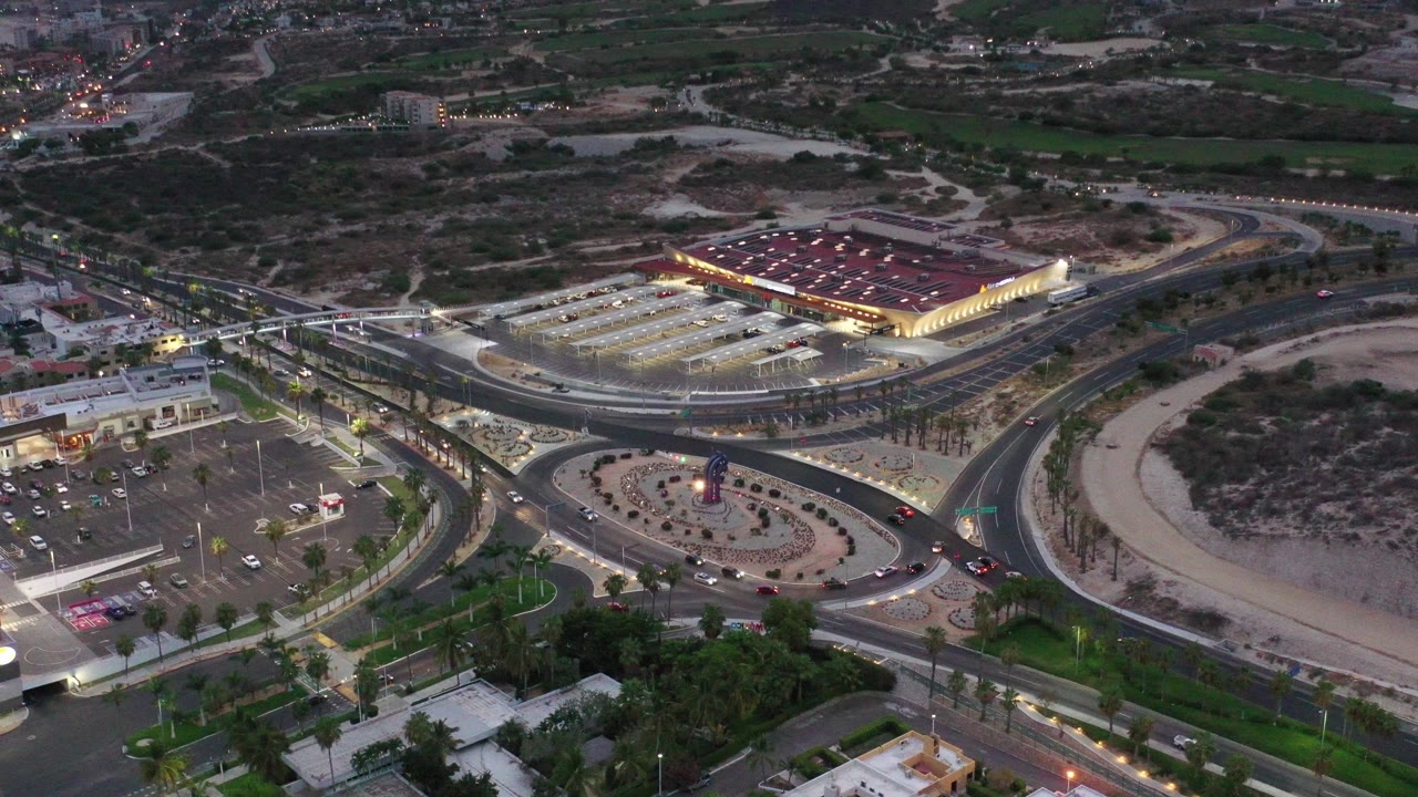 Aerial dusk view of roads, parking lots, and a lit red-roofed building.