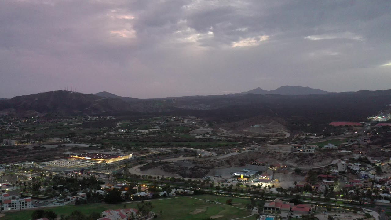 Hillside cityscape with mountains under a cloudy sky
