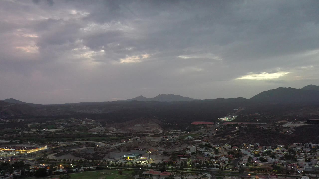 Mountain silhouettes under a heavy cloudy sky.
