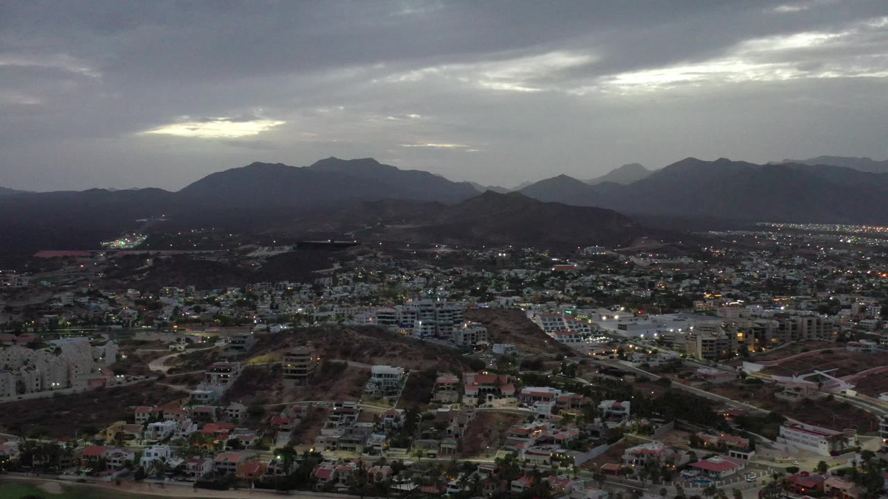 City blocks and hills below a dim mountain skyline.