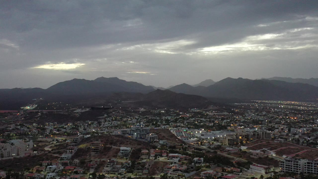 Town lights and roads below dark mountains and cloud cover.